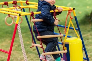 The little baby girl playing at outdoor playground against green grass at autumn