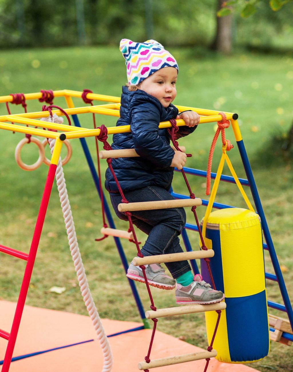 The little baby girl playing at outdoor playground against green grass at autumn